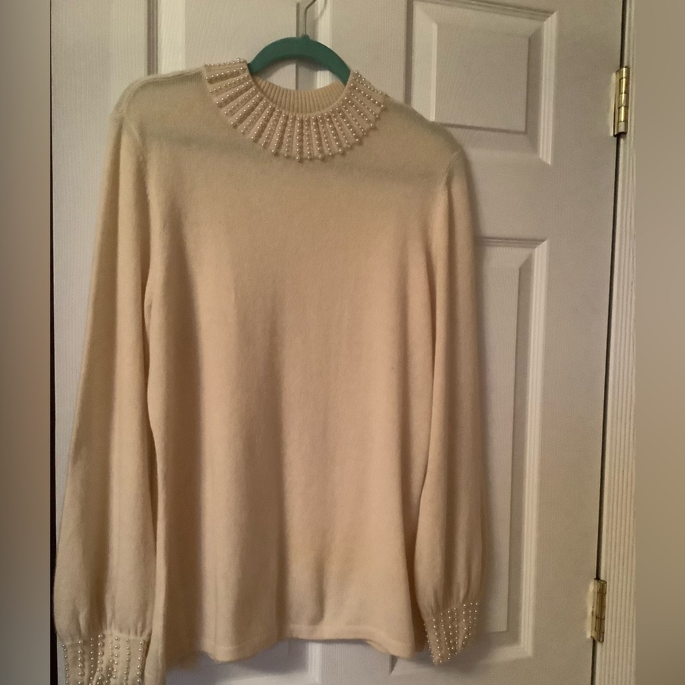 The cashmere sweater with various sized pearls decorate the neckline and cuffs.
